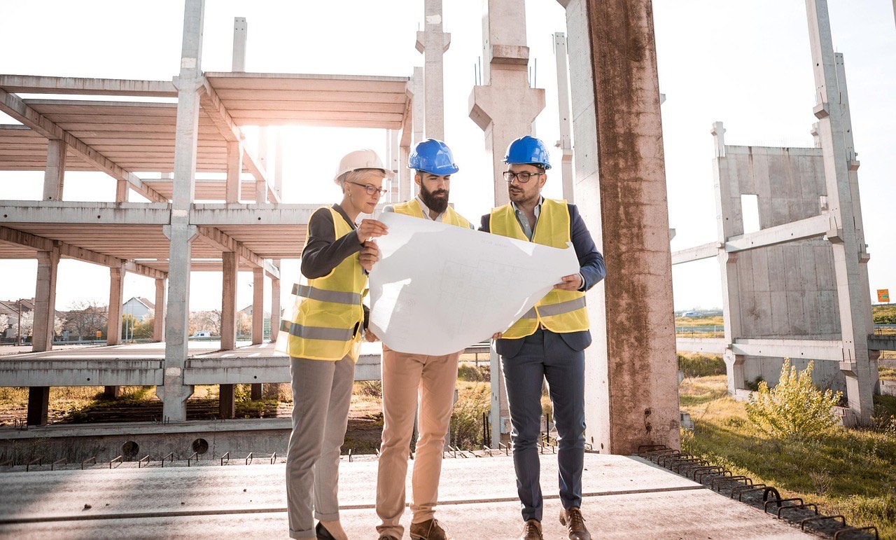 Bauleitung und Planer besprechen Ausführungspläne auf der Baustelle
